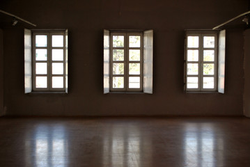 Dark interior with light coming in through three opened windows.