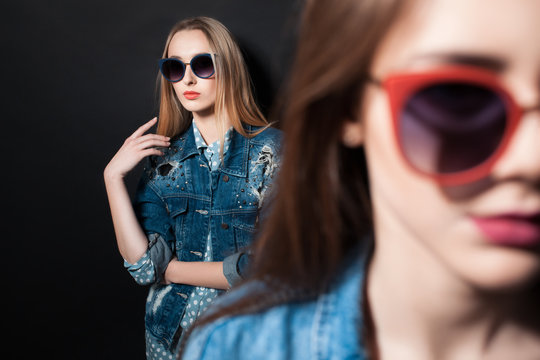 two stylish hipster girls in sunglasses posing;