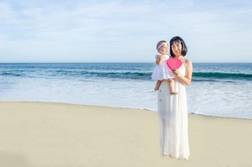 Mother and her baby girl on the sandy beach