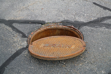 close up on opened rustic manhole cover on the street