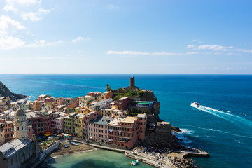 Color full Cinque Terre Vernazza turistic harbor view with boat full of turists in sunny summer day in Italy