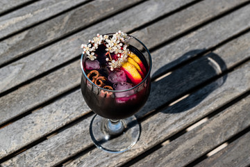 Sangria Cocktail in wine glass with lemon, cinnamon, fruits and ice.