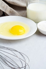 Egg, milk, corolla on white background closeup.