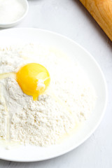 Flour, yolk and rolling pin on a white background.