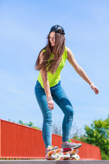Teen girl skater riding skateboard on street.