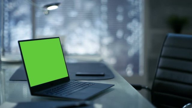  Laptop with Green Mock-up Screen Lies on a Table Modern Minimalist Office.  Shot on RED EPIC-W 8K Helium Cinema Camera.