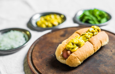 Traditional hot dog with gherkin and mustard relish against white background