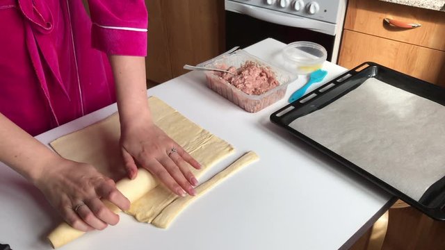 Stages of preparation of meat glomeruli. A woman rolls out the dough. Next to the table is a stuffing and lie tools. Video shot on the iPhone 7 Plus.