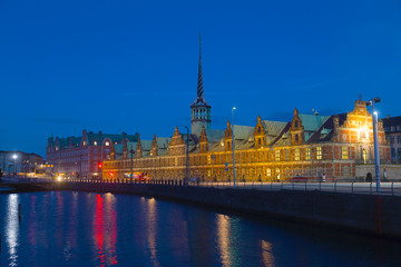 Obraz premium Old Stock Exchange at night in Copenhagen, Denmark. Former stock exchange building along the canal with a distinctive spire.