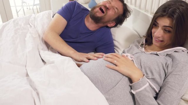 Man and woman pregnant talking about names laughing in bed dolly