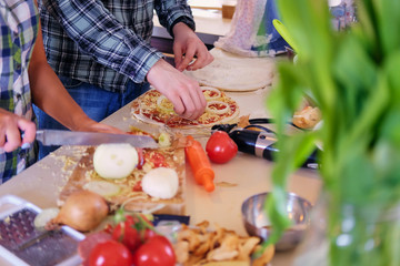 Image from the top view of couple makes pizza in a kitchen.
