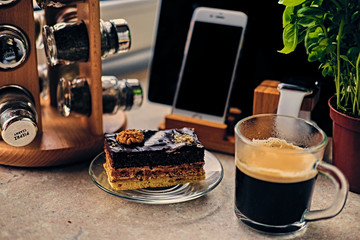 Sweet cake, cup of coffee on a table with smart watch, tablet PC and smart phone.