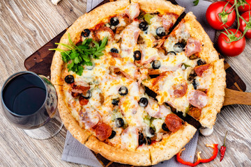 Photo of a hot pizza on wooden background.