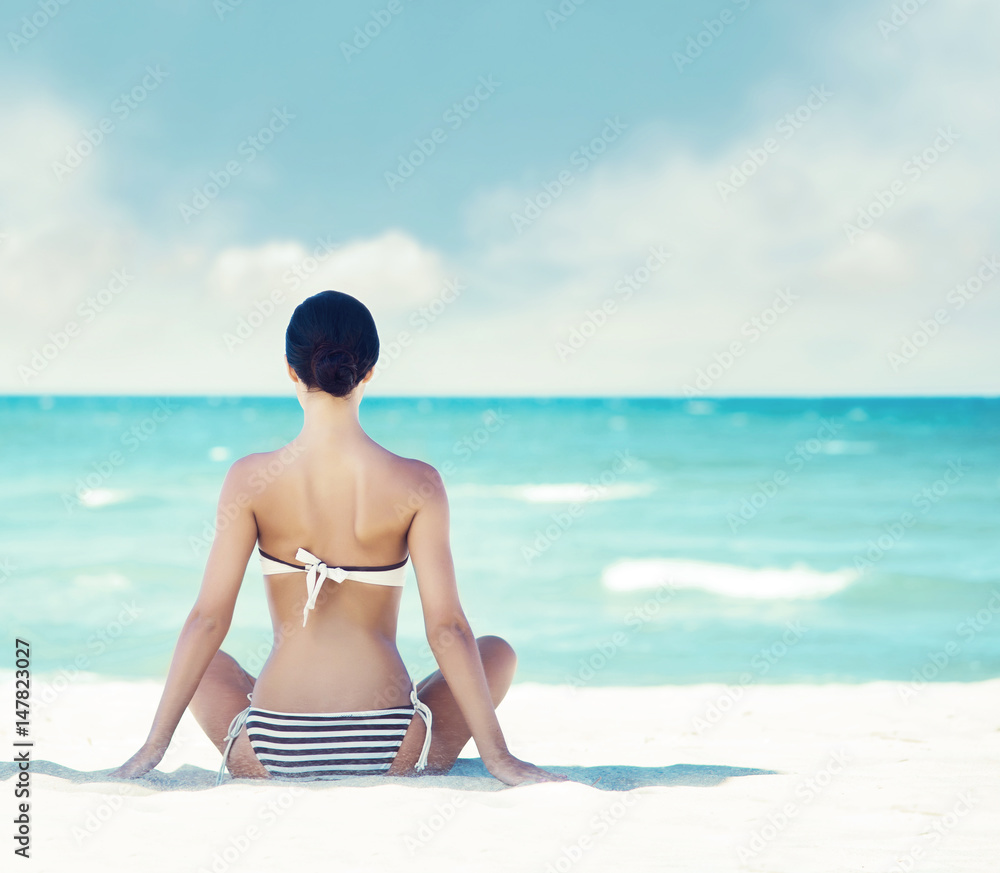 Wall mural young, beautiful and sexy girl meditating on a summer beach. traveling, holiday, vacation, concept.