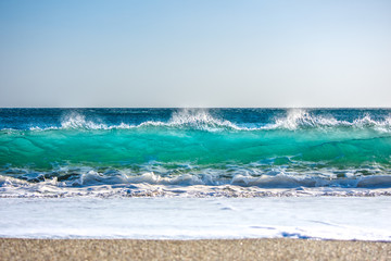 Big wave splashes on a sandy beach, Crete, Greece.