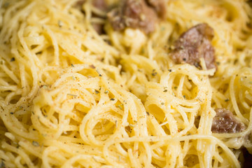 Pasta carbonara in the pan on rustic background. Shallow depth of field.