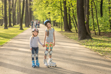 Sisters roller blading together, holding hands