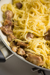 Pasta carbonara in the pan on rustic background. Shallow depth of field.