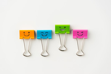 Business concept - Top view of four cute and colourful smile metal clip on white background desk for mockup