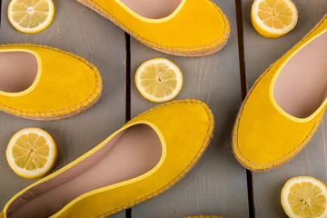Tuinposter Yellow espadrilles shoes near slices of lemon on wooden background. Top view. © bondarillia
