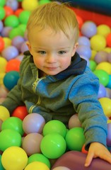 Cute little boy is playing with colorful balls in playcentre.