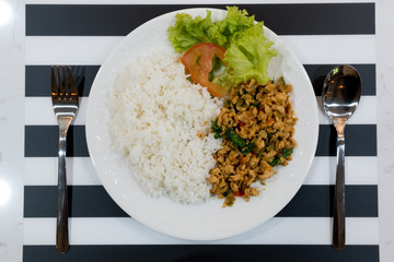 Steamed rice and spicy fried chicken with basil leaves on white dish