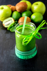 Green smoothie near centimeter and  ingredients for it on black wooden background. Diet. Detox. Healthy drink.