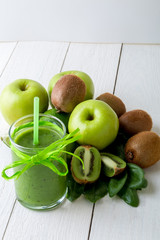 Green smoothie near ingredients for it on white wooden background. Apple, lime, spinach. Detox. Healthy drink.