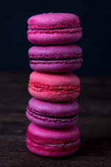 Fototapeta na wymiar Pink macaroons with on dark wooden background. Berry macaroons on dark background. Macaroons close up
