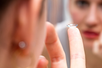 focus of a contact lens held on finger, blurred background
