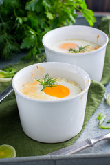 Eggs baked with onions and cheese in white molds, selective focus
