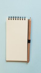 Blank notebook with pencil on blue background, view from above