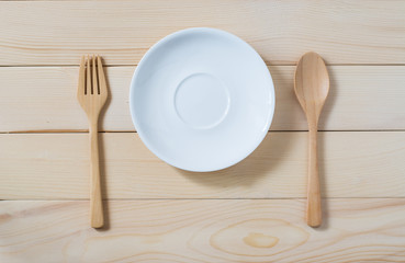 white dish and spoon with wooden spatula put on wooden floor