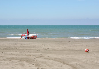 Pattino rosso di salvataggio e ombrellone chiuso sulla spiaggia