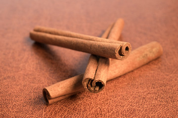 three cinnamon sticks on brown background