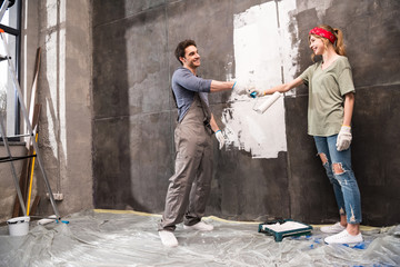 young couple painting wall together, renovation home concept