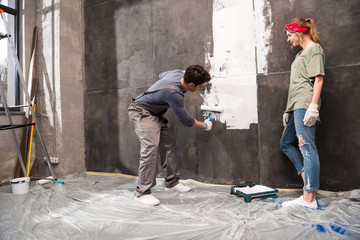 woman looking at man painting wall, renovation home concept