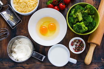 Ingredients for broccoli and tomatoes quiche cooking. Wooden rustic table, top view.
