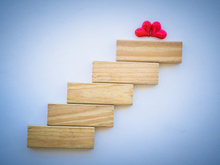 Concept of building LOVE success foundation. two red heart on top of wooden blocks in the shape of a staircase