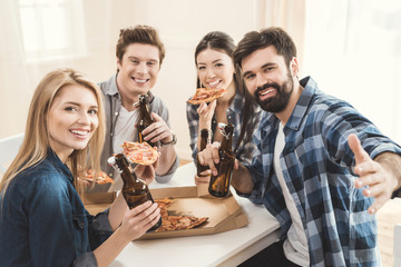 couples drinking beer and eating pizza
