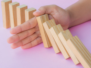 Solution concept with hand stopping wooden blocks from falling in the line of domino