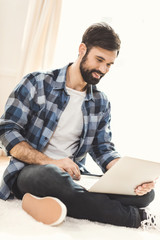 Man sitting on carpet and using laptop