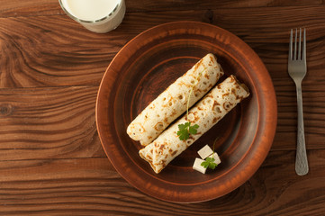 Food photography. Thin pancakes with filling and slices of cheese with herbs