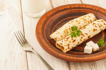 Food photography. Thin pancakes with filling and slices of cheese with herbs