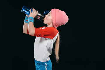 Fototapeta na wymiar girl in sportswear drinking from sport bottle isolated on black. athletics children concept