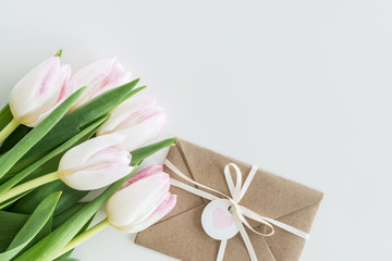light pink tulips and envelope isolated on white with copy space, wedding cards flowers concept