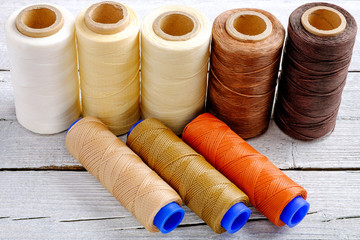 Colorful wax cord, leather thread on white wooden background for leather crafting, wicker work and handcrafts.