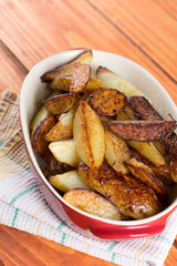 Fried young potatoes in the glass bowl over wooden background