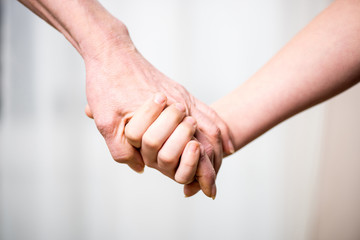 Close-up partial view of grandmother and child holding hands