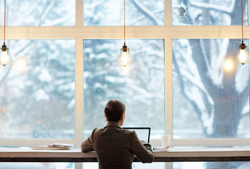 Back view of elegant-looking entrepreneur writing email to her business partner while enjoying...